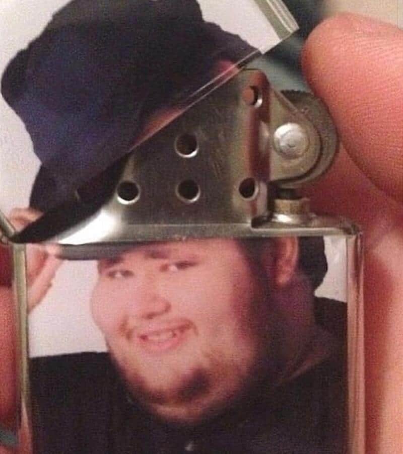 Person holding a lighter with a photo of a young man on it.