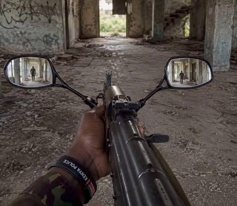 View of a rifle with dual mirrors showing a person in an abandoned building.
