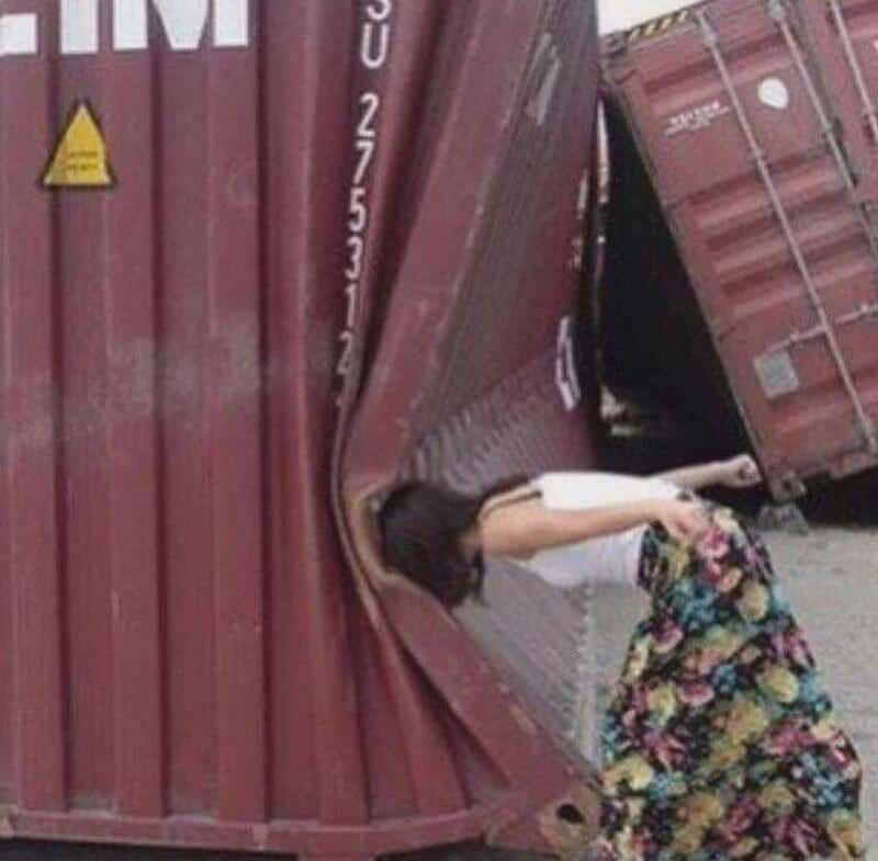 Person leaning into a collapsed shipping container after accident.
