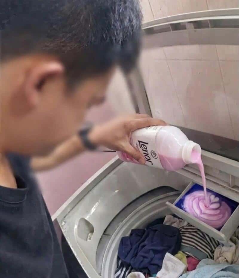 Person pouring pink laundry detergent into washing machine.