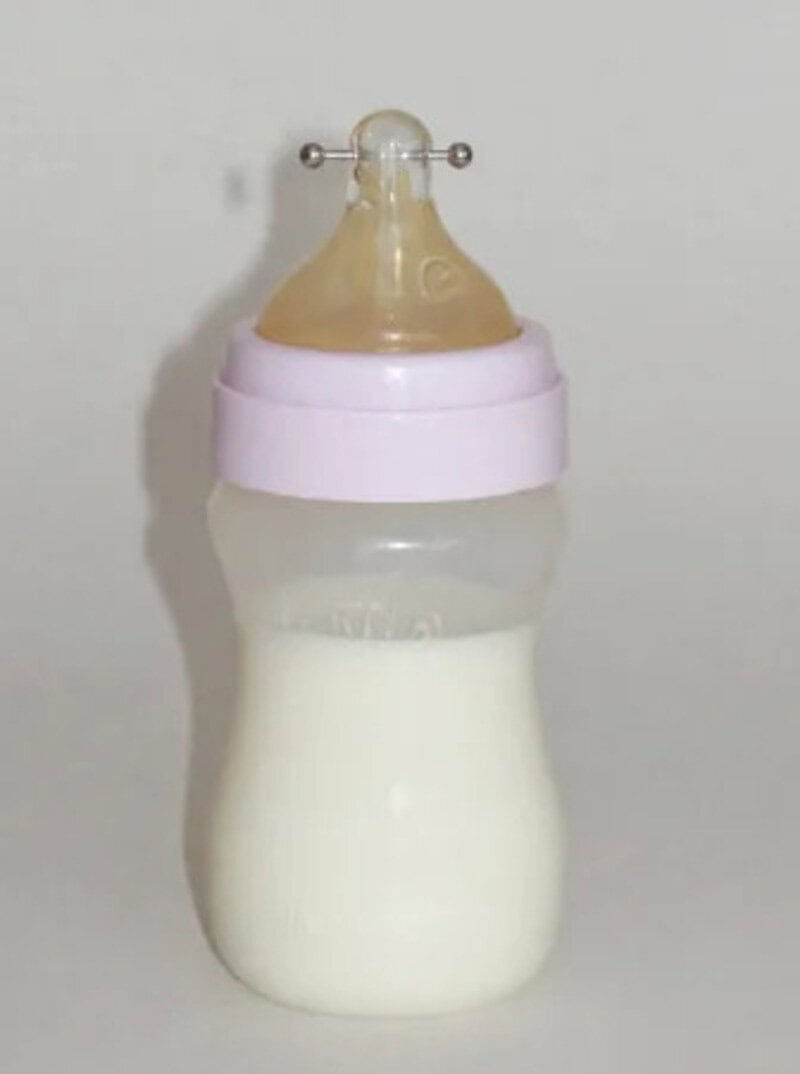 Baby bottle with milk and a nipple on a white background.