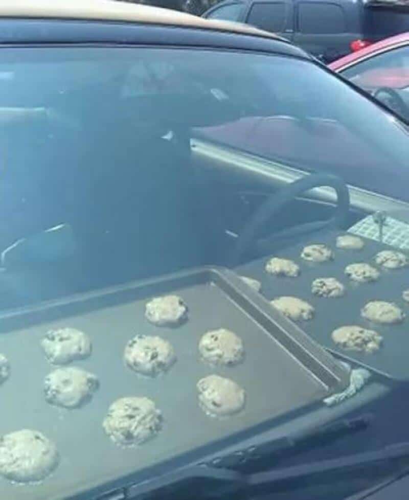 Tray of cookies on a car dashboard, viewed through the windshield.