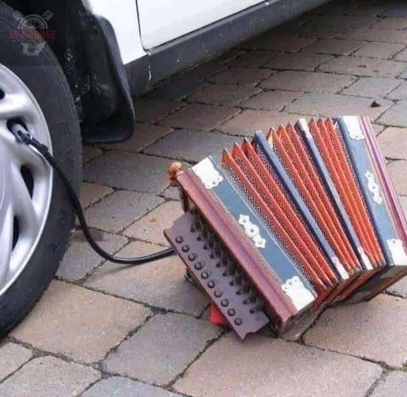 A car is charging with a power strip and a stack of colorful books on the ground.