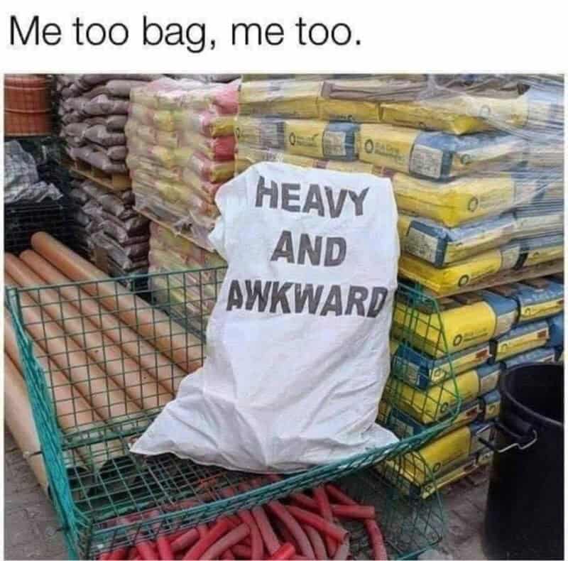 A shopping cart with a bag that says 'Heavy and Awkward' in a store aisle.