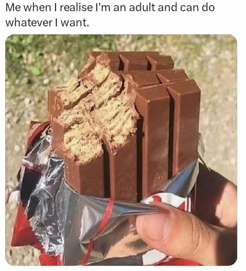 Adult holding a partially unwrapped chocolate bar with broken pieces.