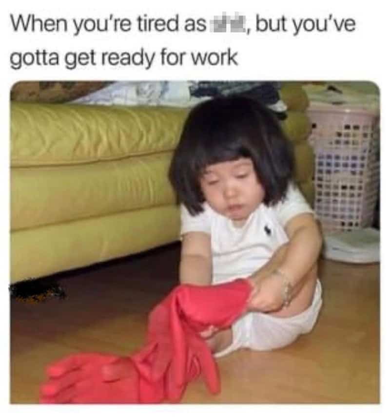 Child tiredly holding a red shirt, sitting on the floor in a living room.