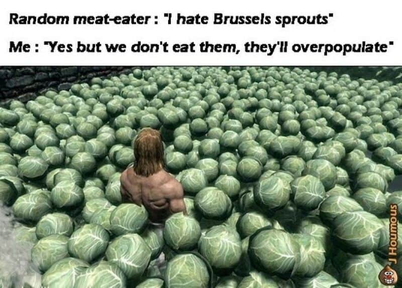 A person with long hair is surrounded by a large number of Brussels sprouts.