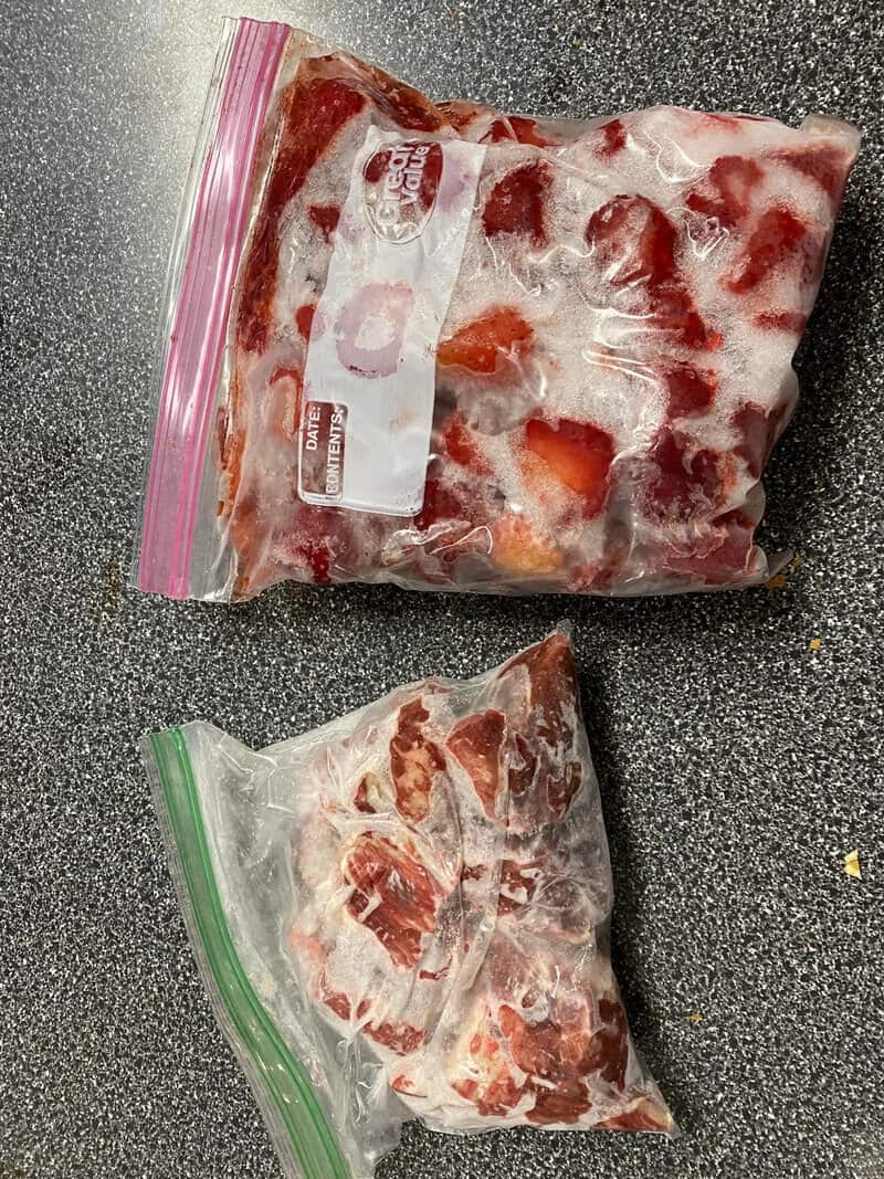 Frozen meat in a plastic bag on a gray surface.