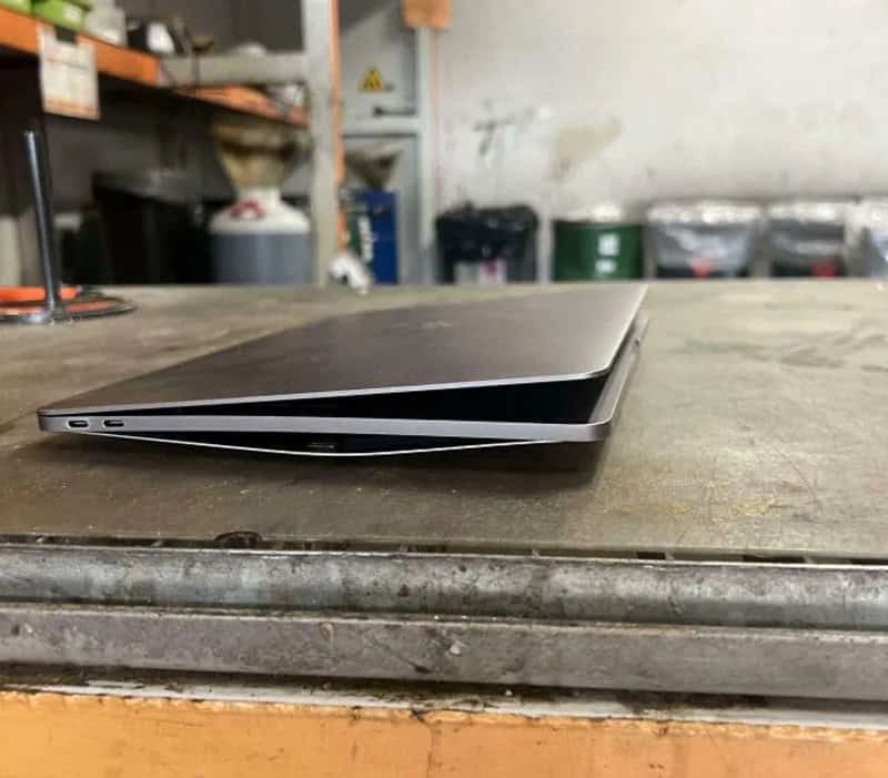 Two laptops stacked on a workbench in a workshop.