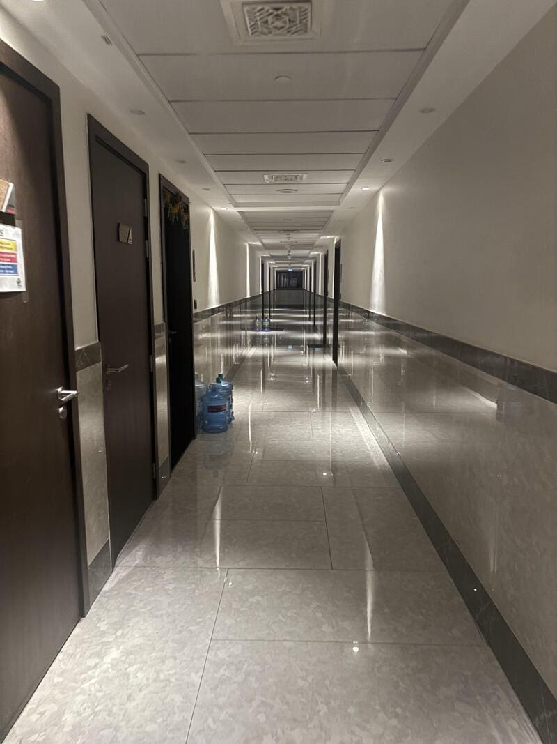 Long, empty corridor with doors and a water bottle on the floor.