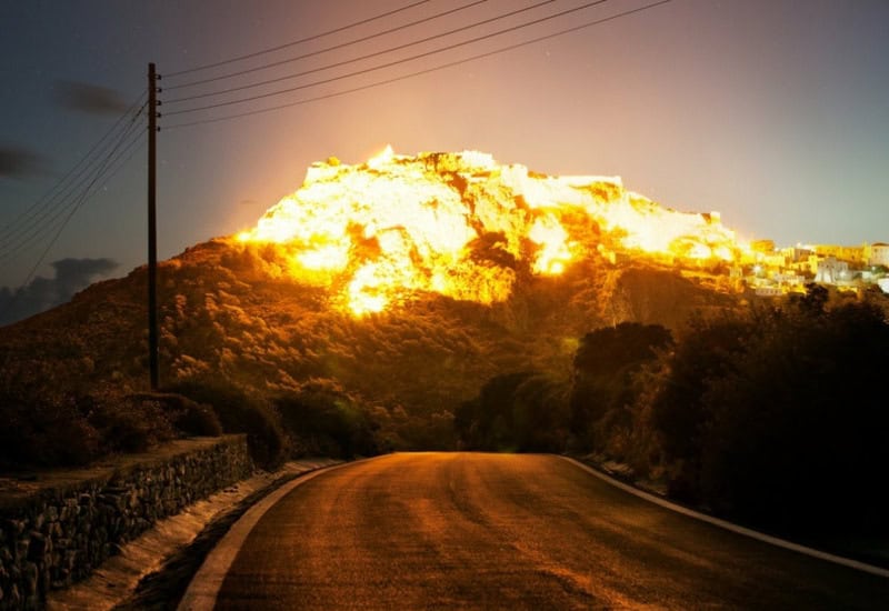 Bright explosion on a mountain with a road in the foreground.