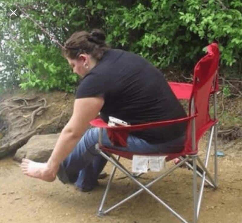 Woman sitting on a red chair with her foot in a small stream of water.