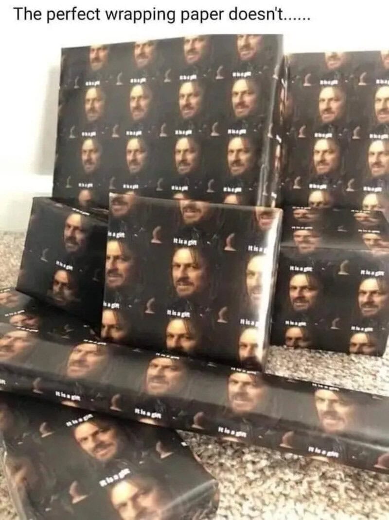 Image of multiple rolls of wrapping paper with a man's face printed on them.