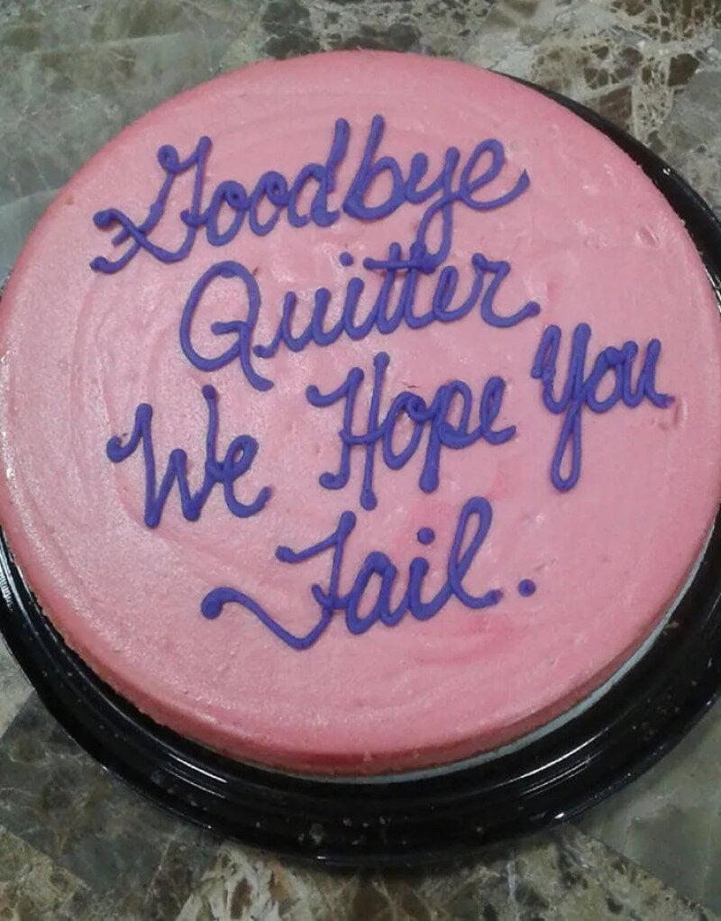 Pink cake with purple writing saying 'Goodbye Quitter We Hope You Fail'.