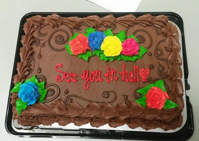 Chocolate cake with colorful flowers and 'See you in hell' written in red.