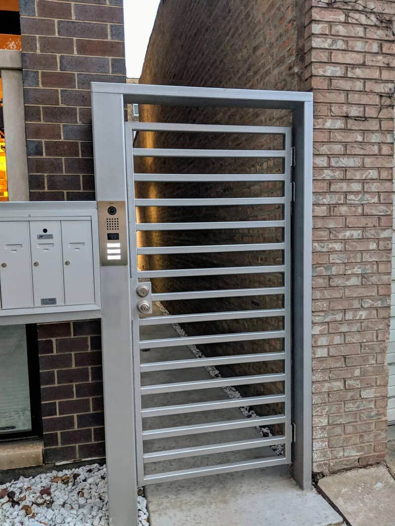 Metal gate with horizontal bars in front of brick wall, part of a home improvement fail.