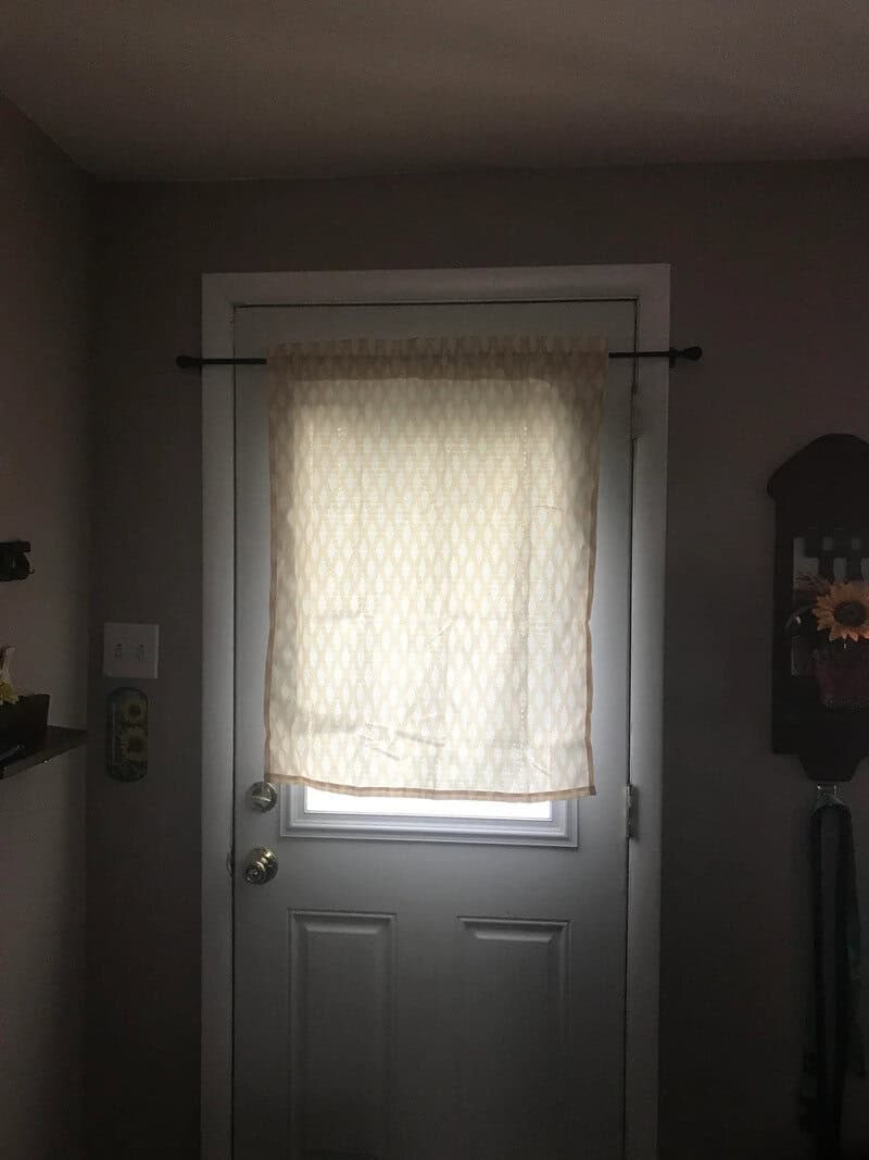 Door with a curtain covering the window, in a room with gray walls.