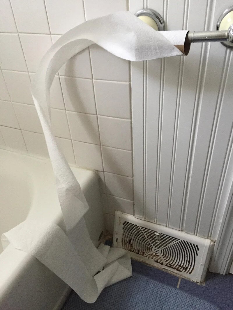 Toilet paper roll is unrolled and hanging over a radiator cover.