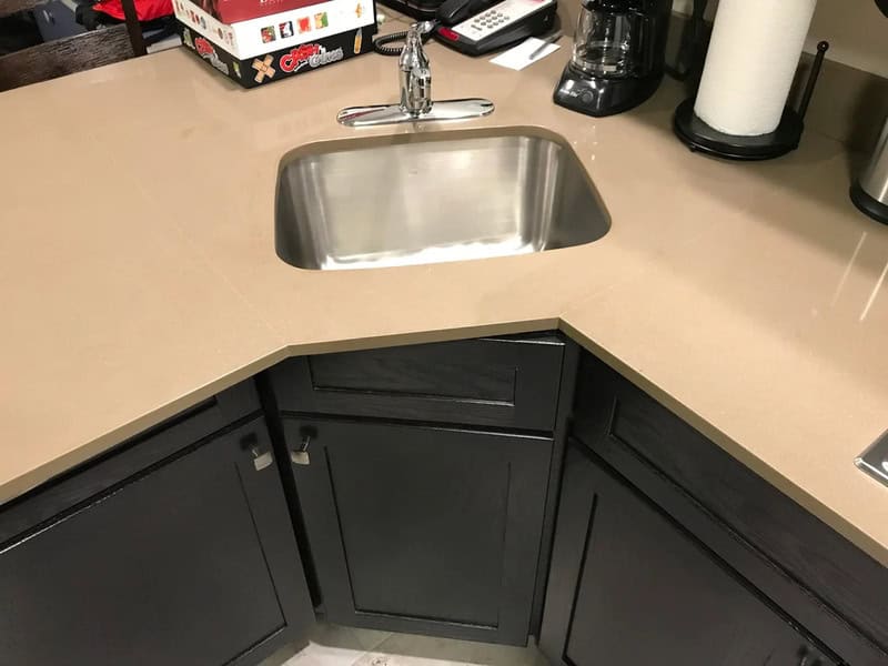 Kitchen with a sink and black cabinets, corner layout, with coffee maker and paper towel roll.