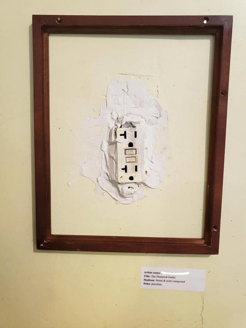 Electrical outlet with a torn wall and a wooden frame around it.