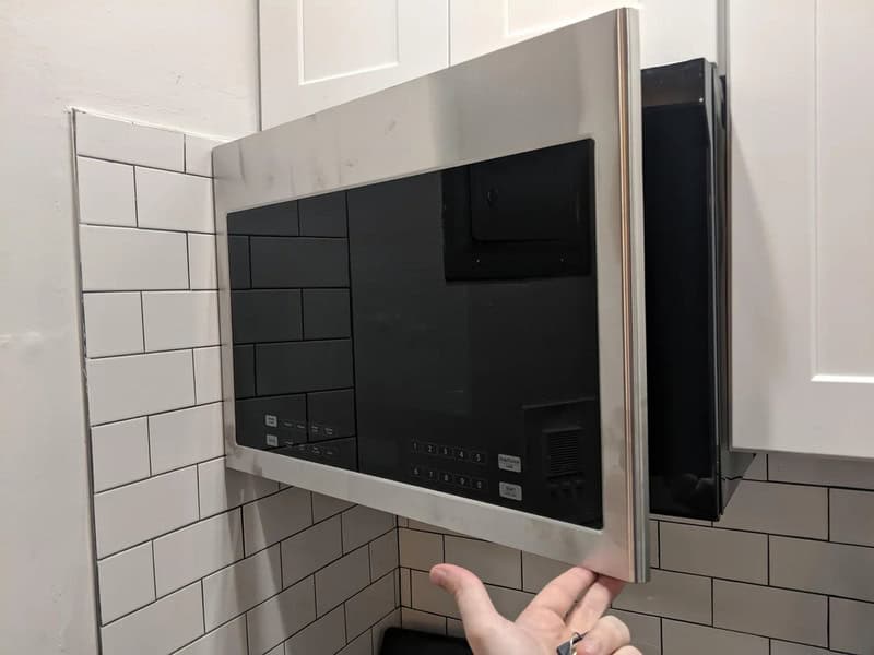 Microwave oven installed over a stove in a kitchen.