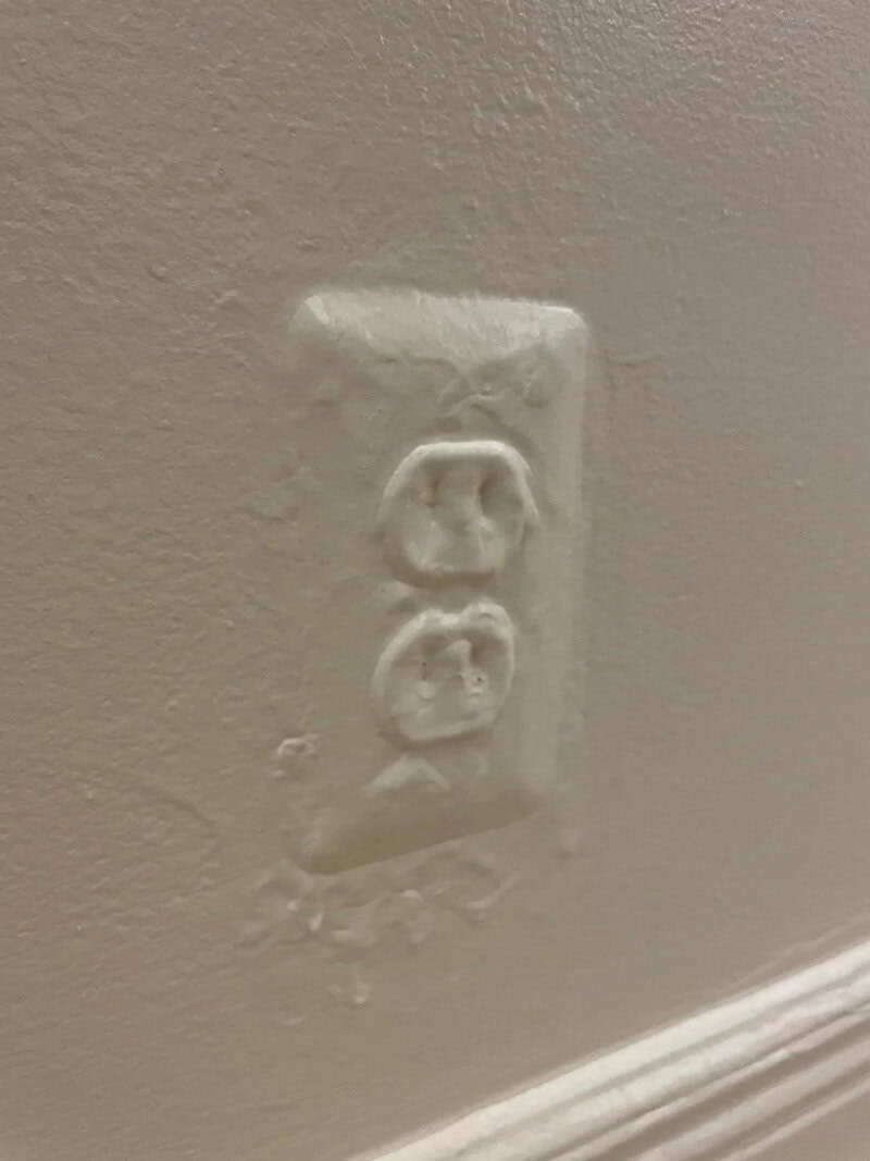 Damaged electrical outlet with missing cover plate on wall.