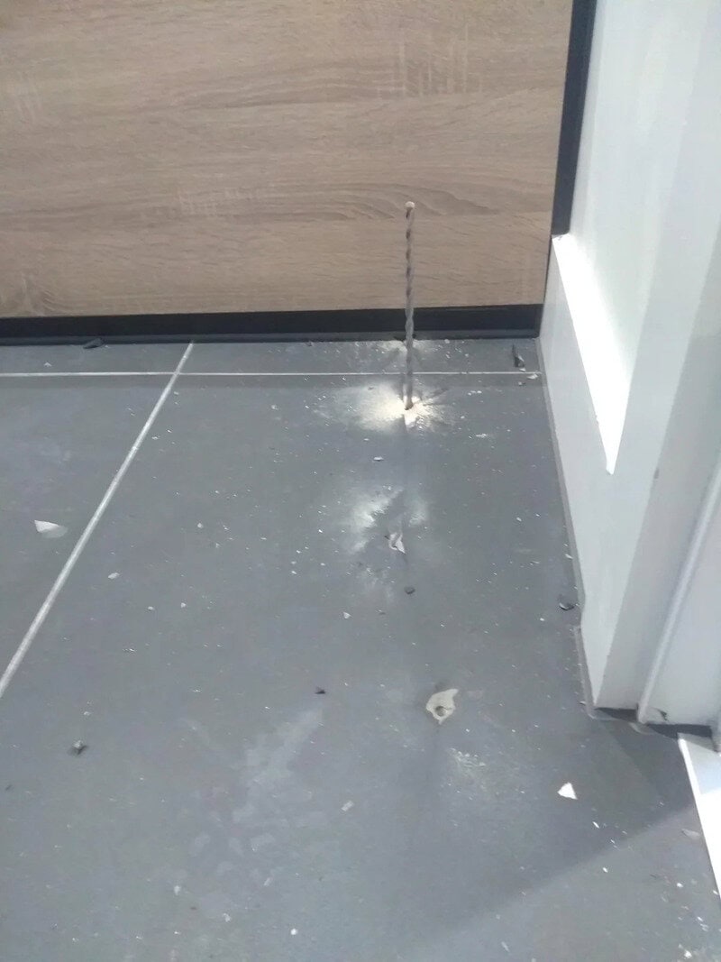 Broken pipe leaking water onto tiled floor near door.
