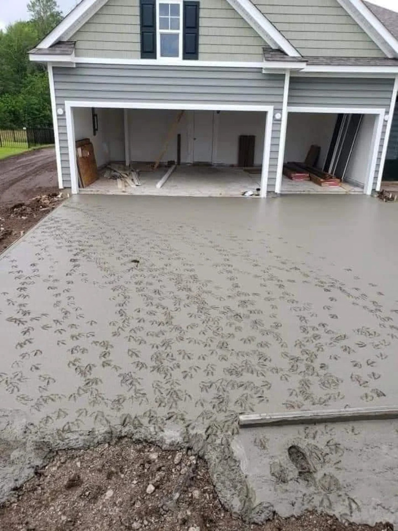 Concrete driveway with footprints leading to a garage under construction.
