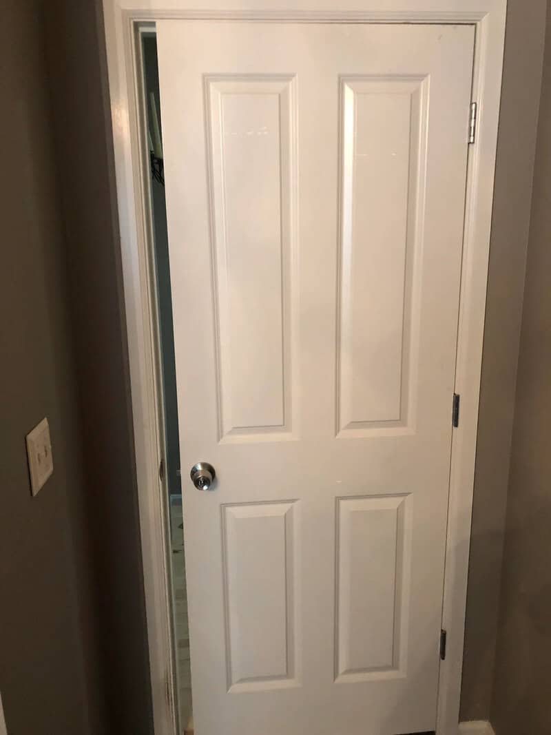 White door with a missing handle and a gap at the bottom.