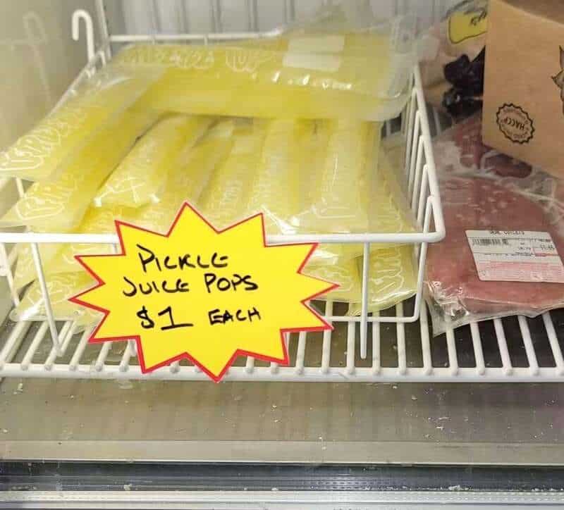 Sign on store shelf reads 'Pickle Juice Pops $1 Each' in yellow starburst shape.
