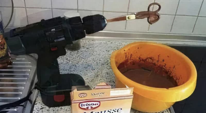 A drill attached to a stick, with a bowl of chocolate pudding nearby.