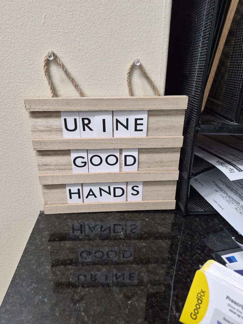 Sign reads 'URINE GOOD HANDS' with a humorous message.