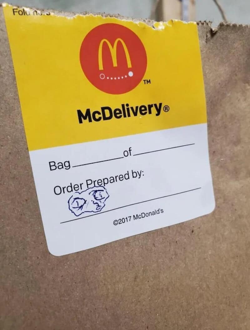 McDonald's McDelivery bag label with handwritten doodles of faces.