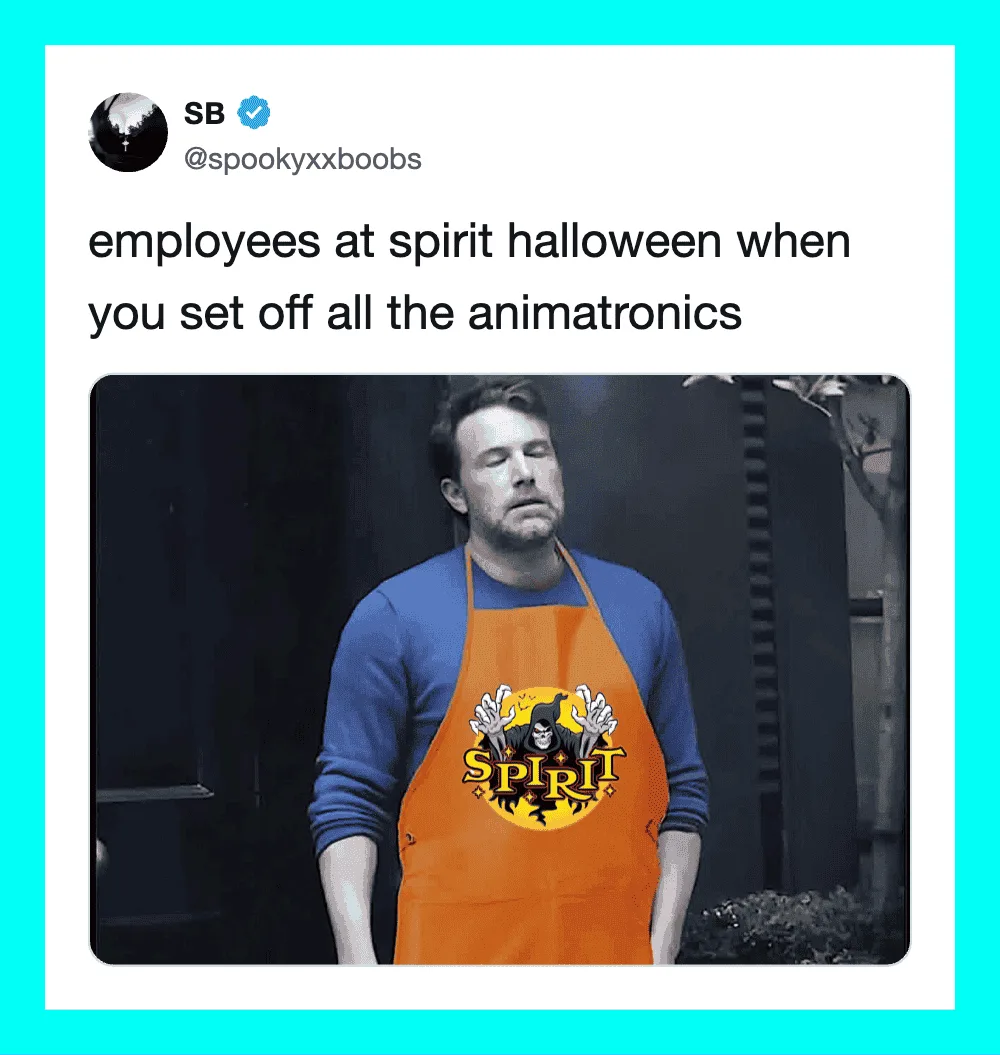 Employee at Spirit Halloween wearing an orange apron with a black panther logo, looking tired.
