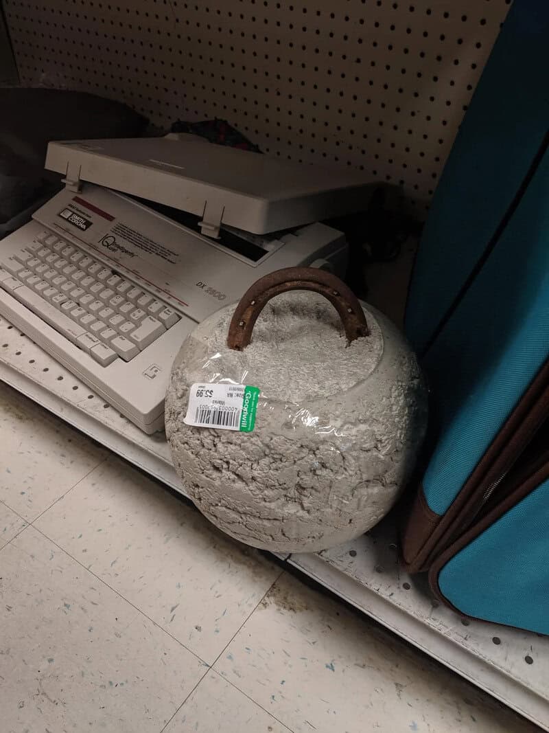 A large, round, cracked ceramic pot with a handle, placed on a store shelf.