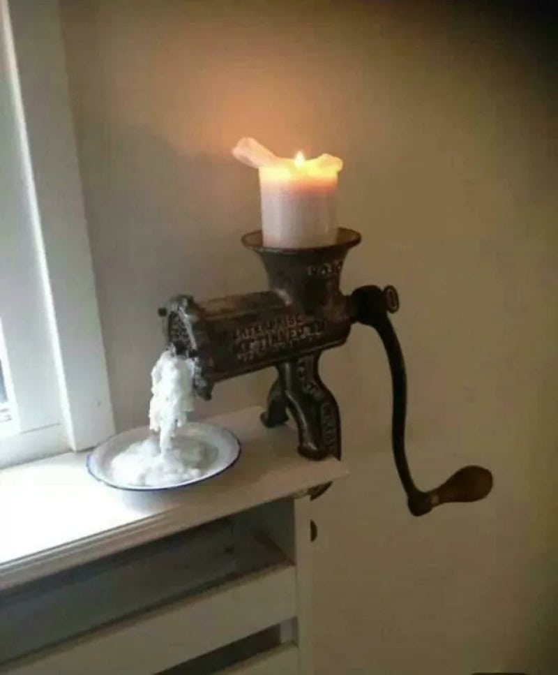 Candle on a vintage manual coffee grinder with water pouring out.