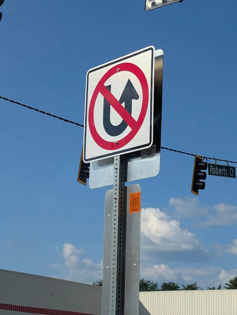 No U-turn sign on a pole with a street sign for Roberts Ct.