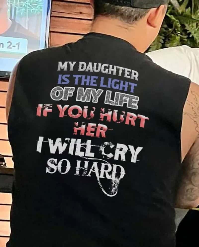 Back of a person wearing a black sleeveless shirt with a message about daughter.