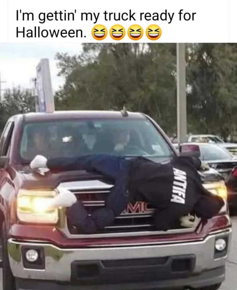 Person in a black hoodie with 'MUTTER' on the back, lying on a truck's hood.