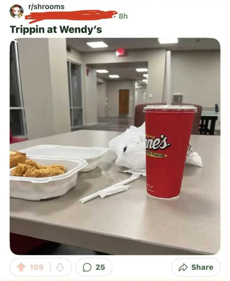 Empty Wendy's dining area with a large soda and food containers on the table.