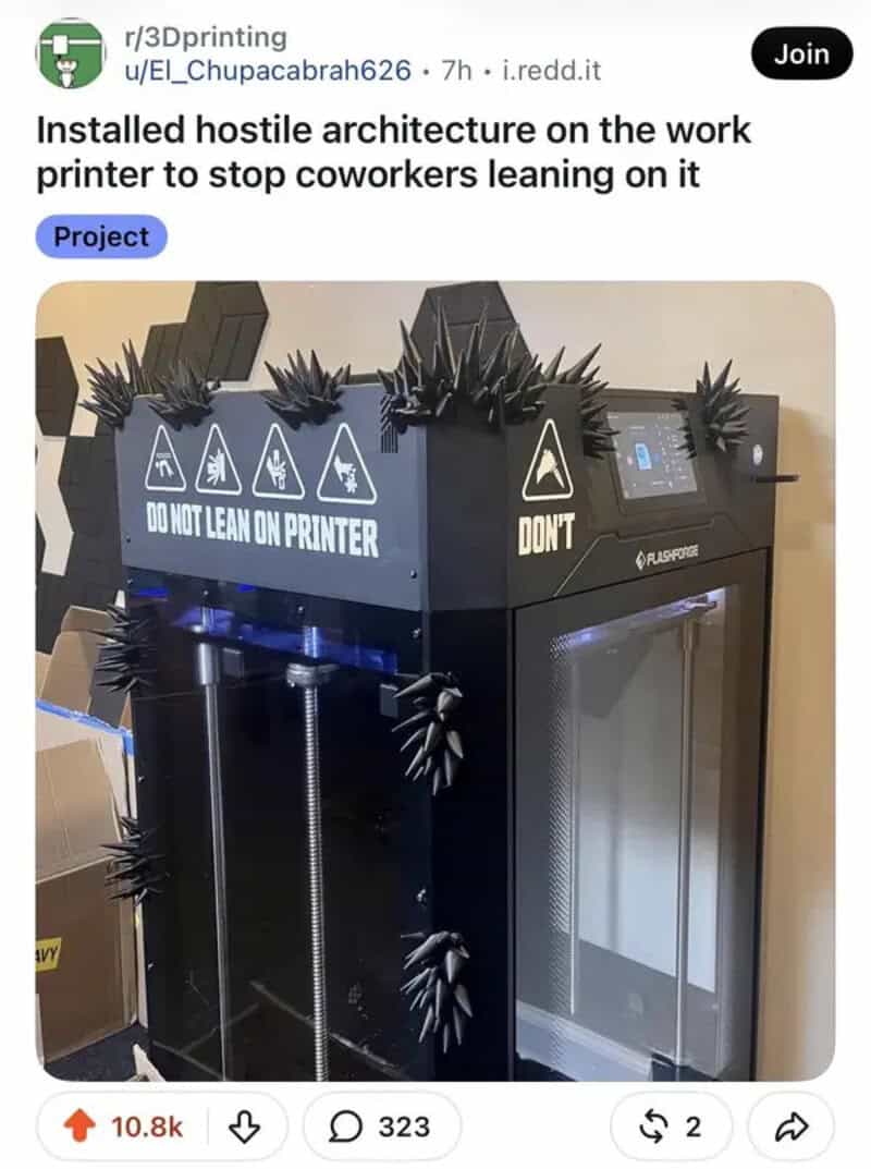 Printer with hostile architecture spikes to prevent leaning, with warning signs.