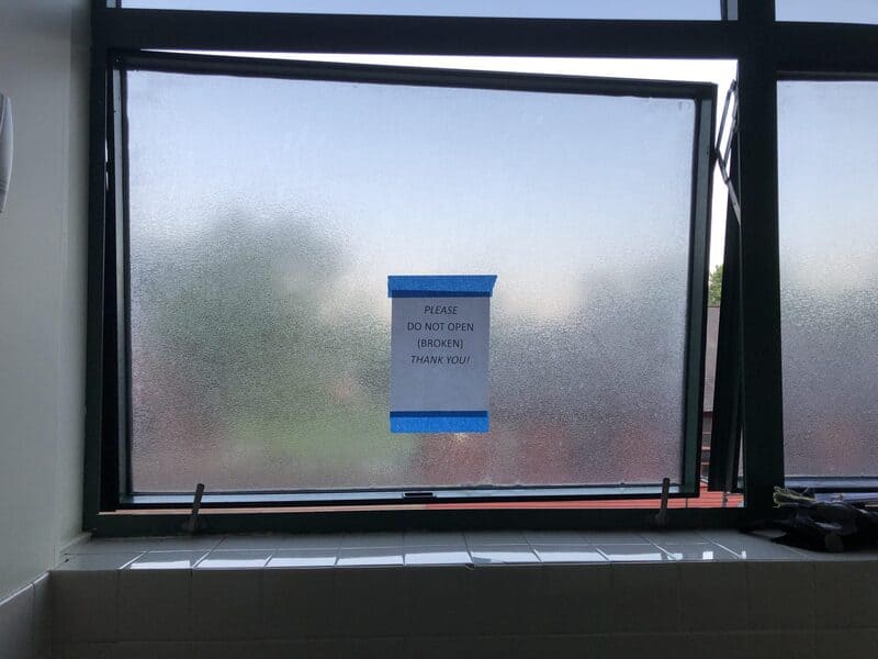 Frosted window with a sign that says 'Please do not open (broken) thank you!'.