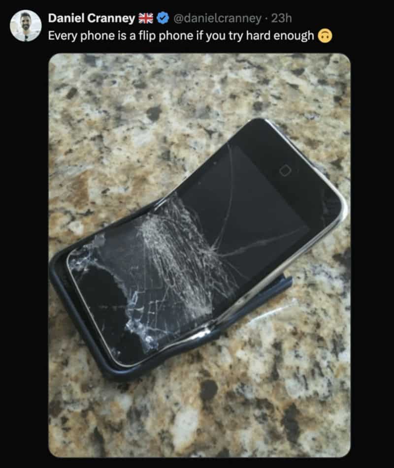 Broken flip phone on a granite surface with a cracked screen.