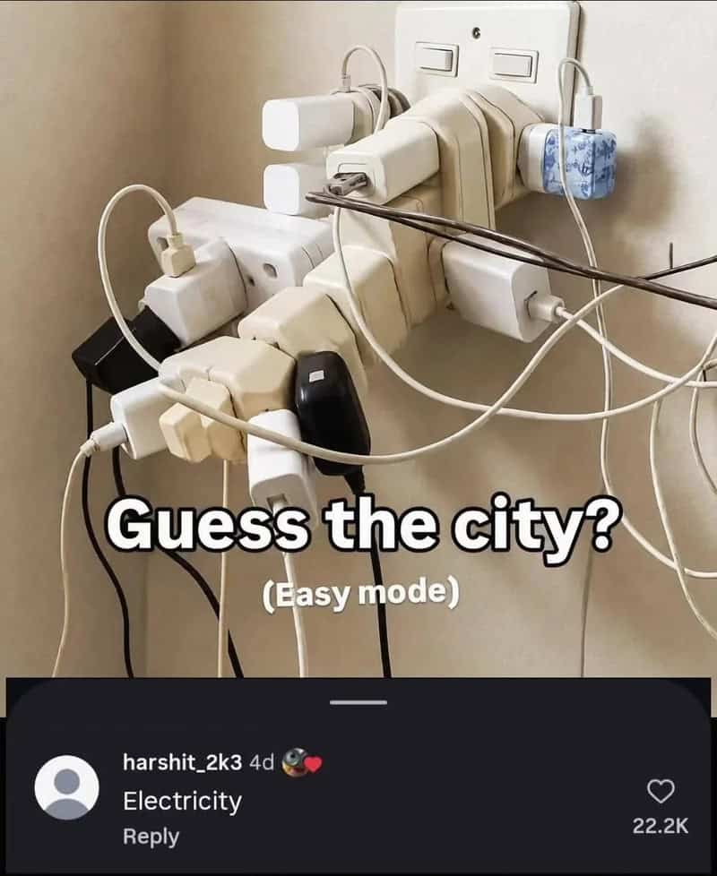 Tangled electrical cords plugged into a wall socket with a caption about guessing the city.