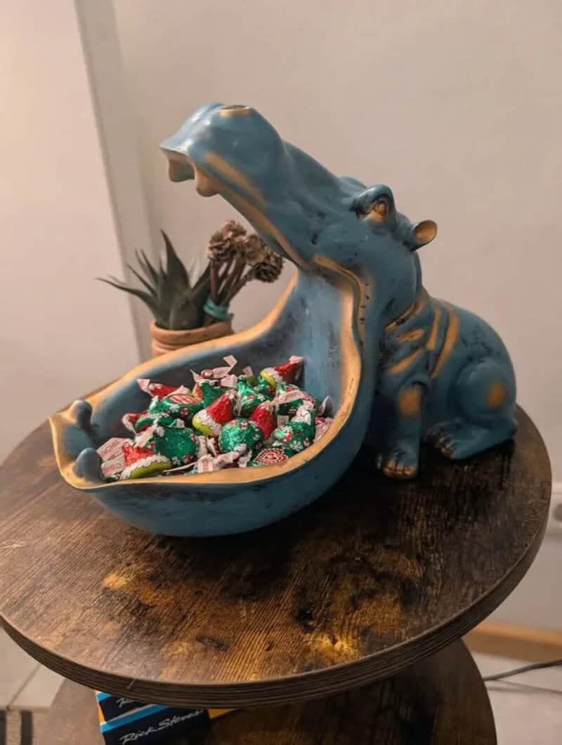 Hippo-shaped candy dish filled with colorful candies on a wooden table.