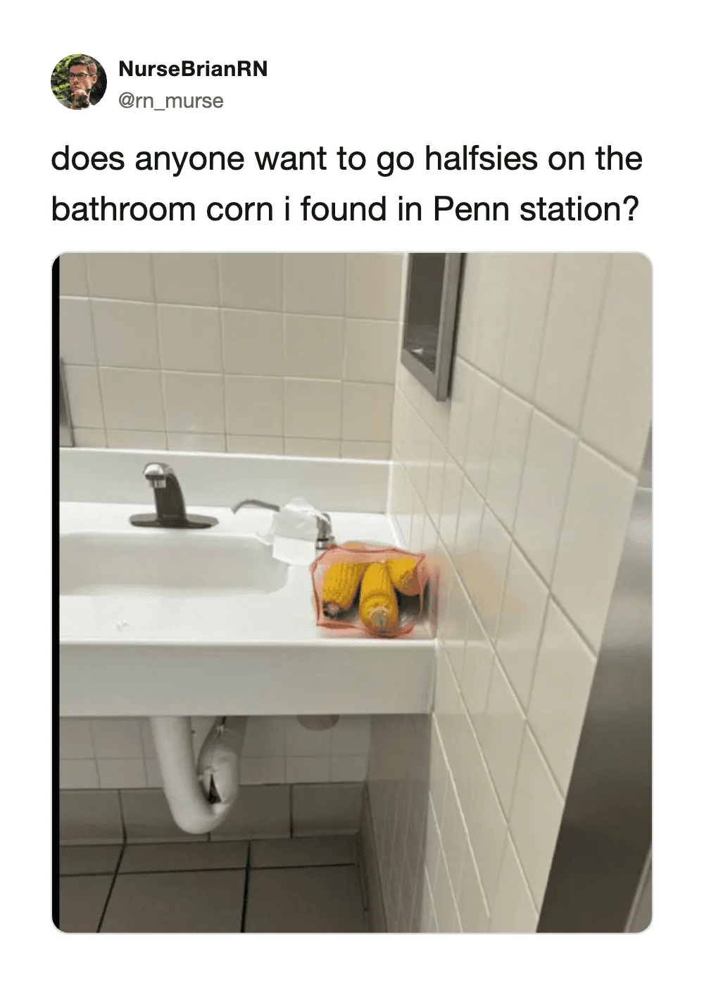 Bathroom sink with a pink container holding two yellow corn on the cob halves.