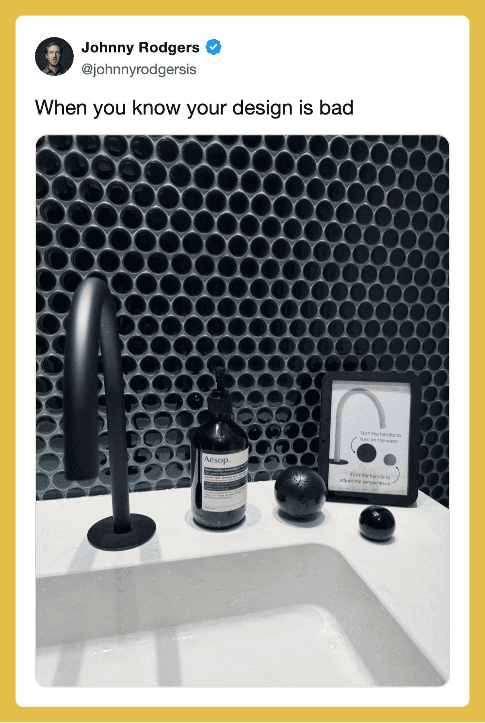 Bathroom sink with a black faucet, Aesop soap, and black decor against a honeycomb-patterned wall.