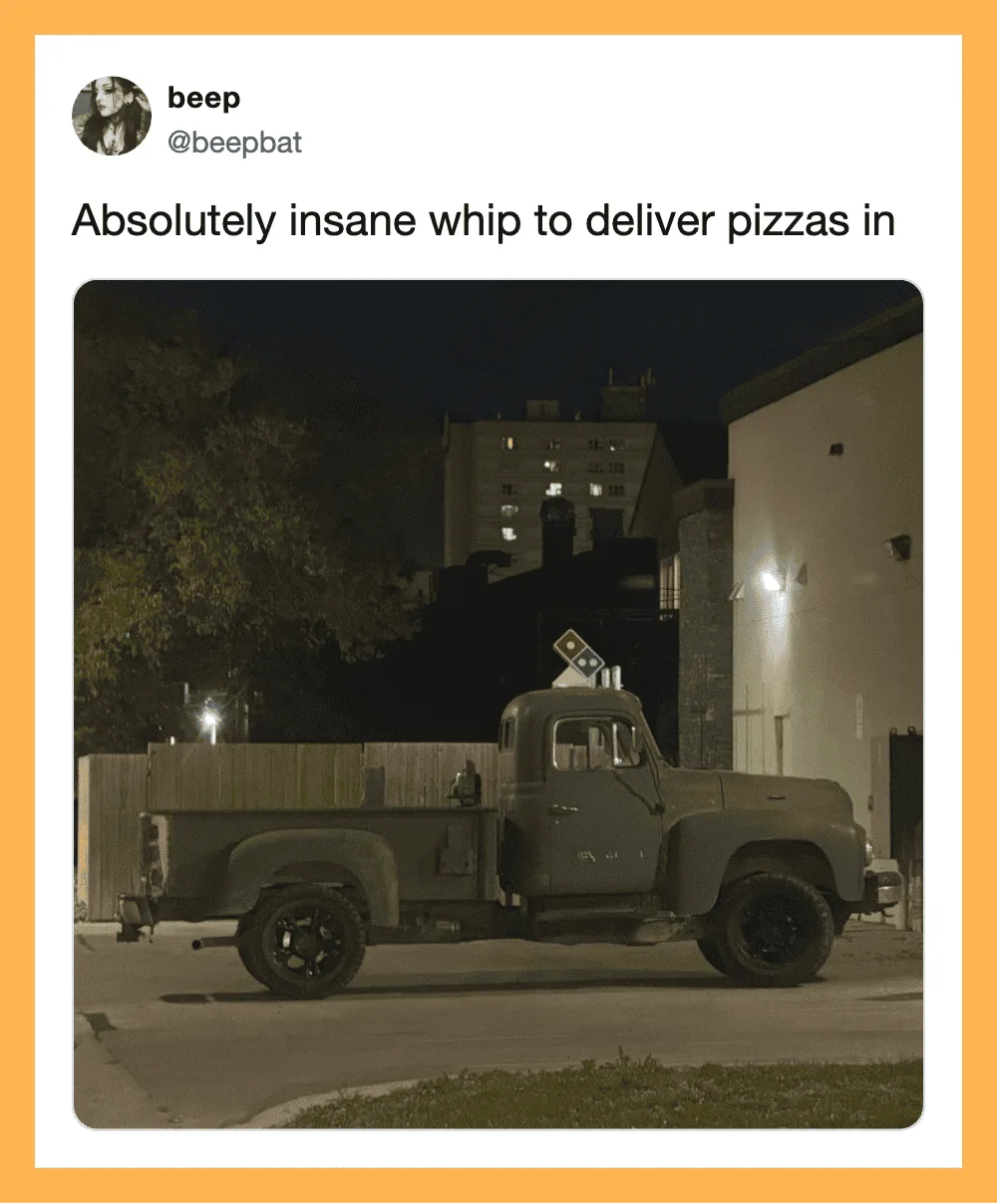 Green truck with Domino's pizza box on the back at night.