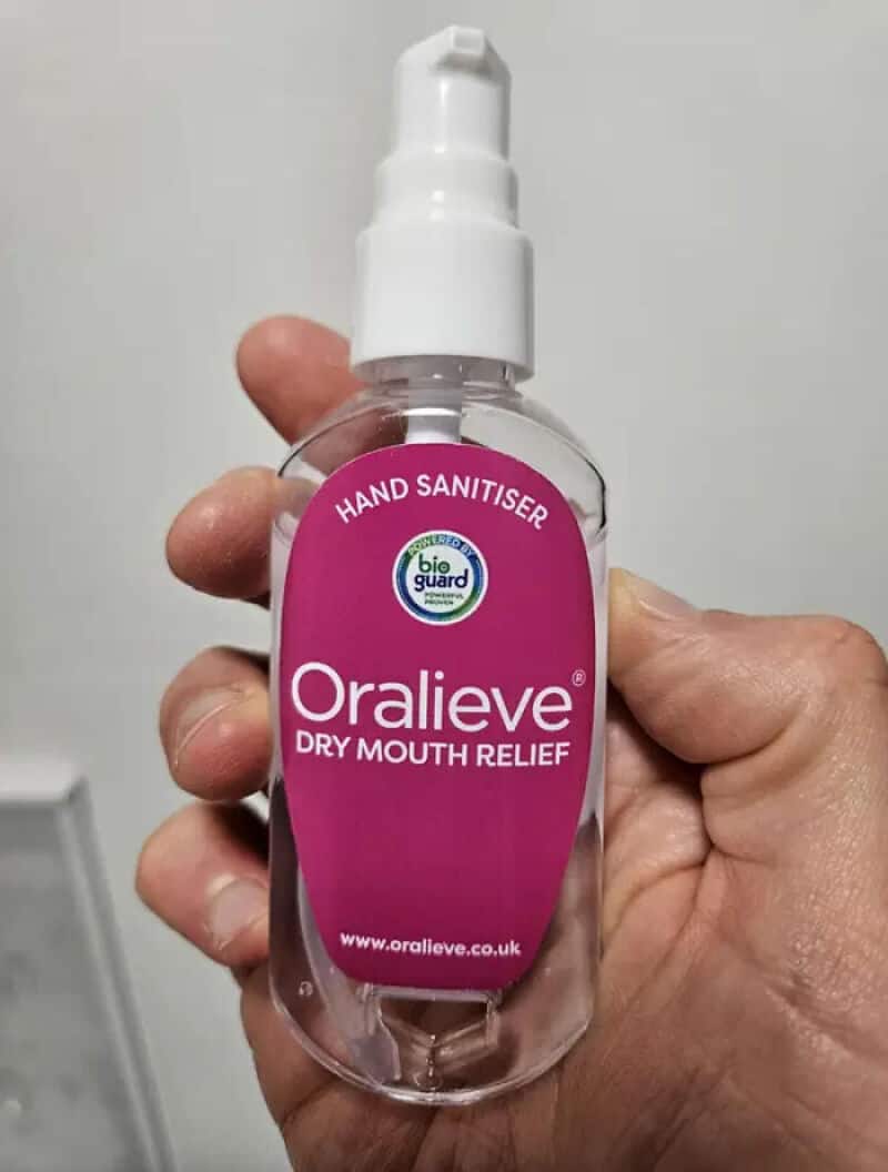 Oralieve hand sanitizer spray bottle with pink label and white spray cap.