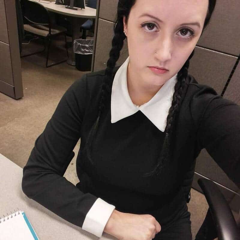 Young woman with braided hair and serious expression in an office setting.